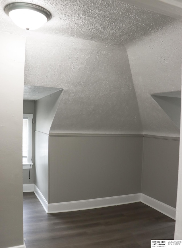 bonus room with dark hardwood / wood-style floors, vaulted ceiling, and a textured ceiling