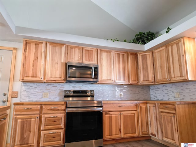 kitchen with lofted ceiling, backsplash, dark hardwood / wood-style floors, and appliances with stainless steel finishes