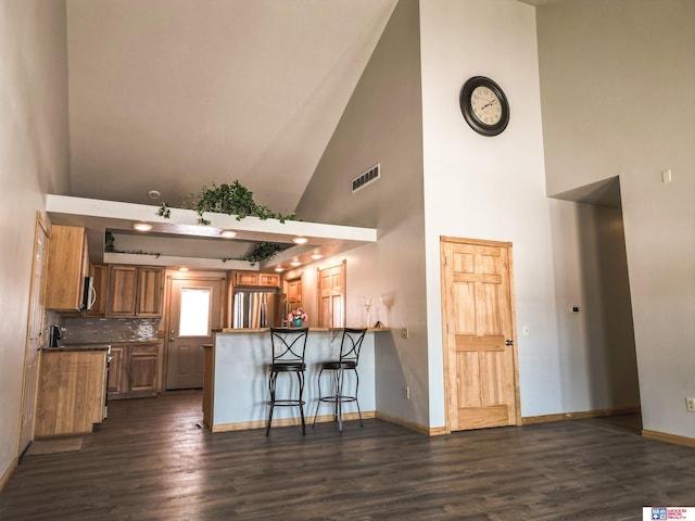 kitchen featuring appliances with stainless steel finishes, a breakfast bar, dark hardwood / wood-style floors, and kitchen peninsula