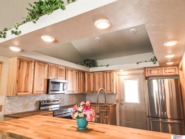 kitchen featuring stainless steel appliances, tasteful backsplash, and butcher block countertops