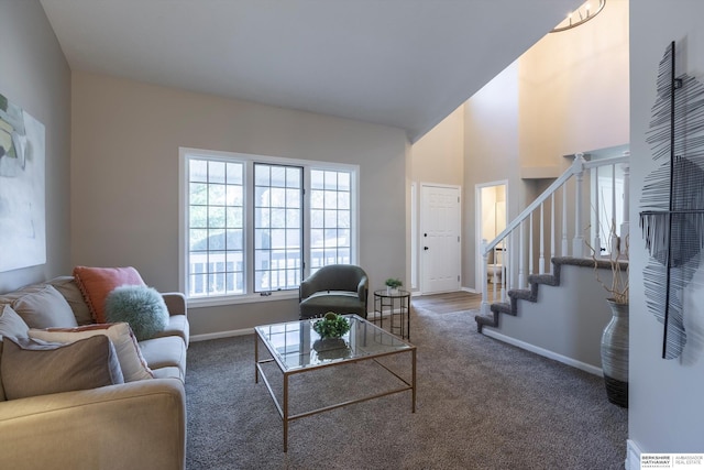 living room featuring a towering ceiling and dark carpet