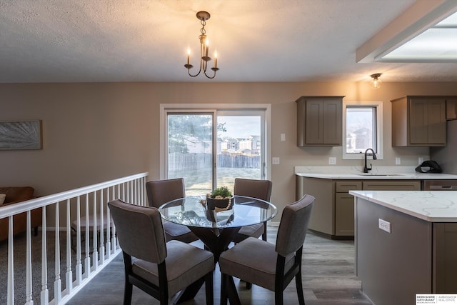 dining room with an inviting chandelier, sink, hardwood / wood-style floors, and a textured ceiling