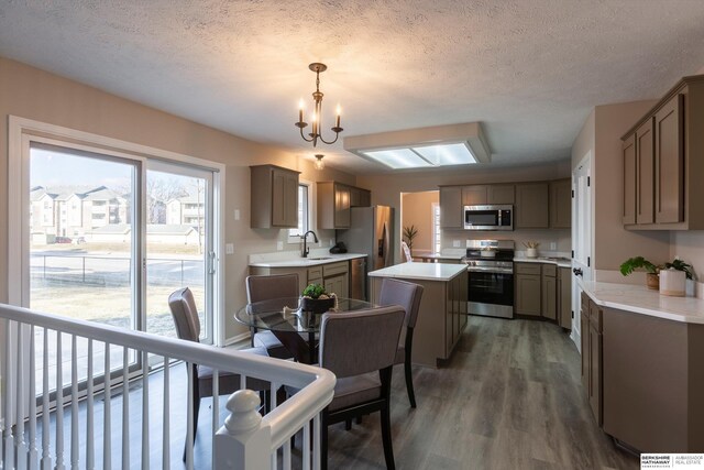 kitchen with sink, stainless steel appliances, dark hardwood / wood-style floors, a center island, and decorative light fixtures