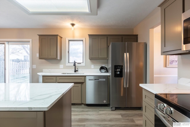 kitchen featuring light wood-type flooring, stainless steel appliances, sink, and a wealth of natural light