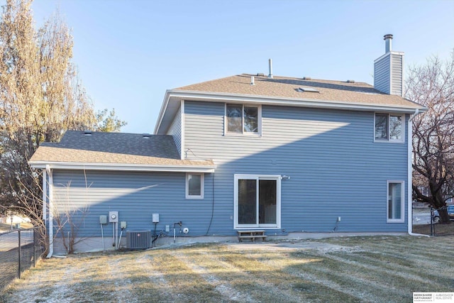 back of house with central AC unit and a lawn