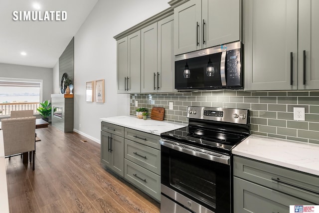 kitchen with stainless steel appliances, gray cabinets, tasteful backsplash, light stone counters, and dark wood-type flooring