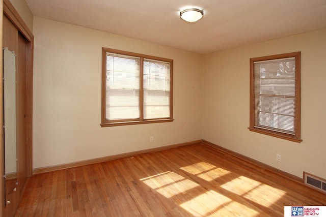 spare room with light wood-style flooring, visible vents, and baseboards