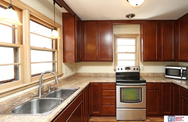 kitchen featuring appliances with stainless steel finishes, pendant lighting, a sink, and light countertops