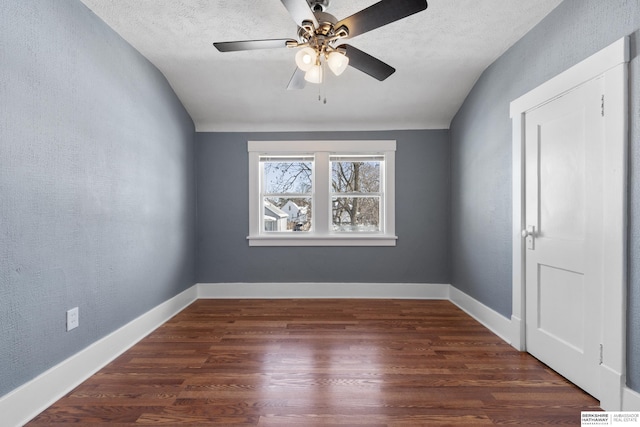 empty room featuring dark hardwood / wood-style flooring, vaulted ceiling, and a textured ceiling