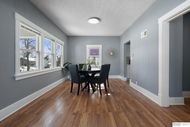 dining area with dark hardwood / wood-style floors and a textured ceiling