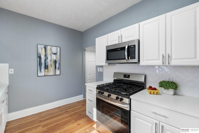 kitchen with tasteful backsplash, light hardwood / wood-style floors, white cabinets, and appliances with stainless steel finishes