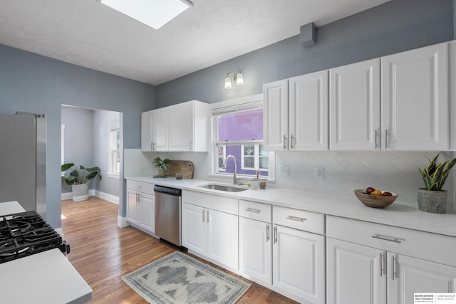 kitchen featuring sink, white cabinetry, tasteful backsplash, light wood-type flooring, and appliances with stainless steel finishes