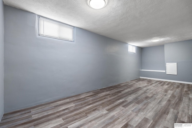 basement featuring a textured ceiling and light hardwood / wood-style floors