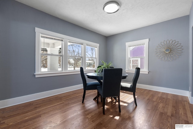 dining space featuring dark wood-type flooring and a textured ceiling