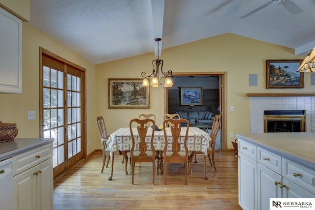 dining room featuring ceiling fan with notable chandelier, lofted ceiling, a fireplace, and light hardwood / wood-style floors