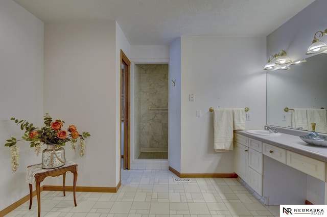 bathroom with vanity, a textured ceiling, and a tile shower