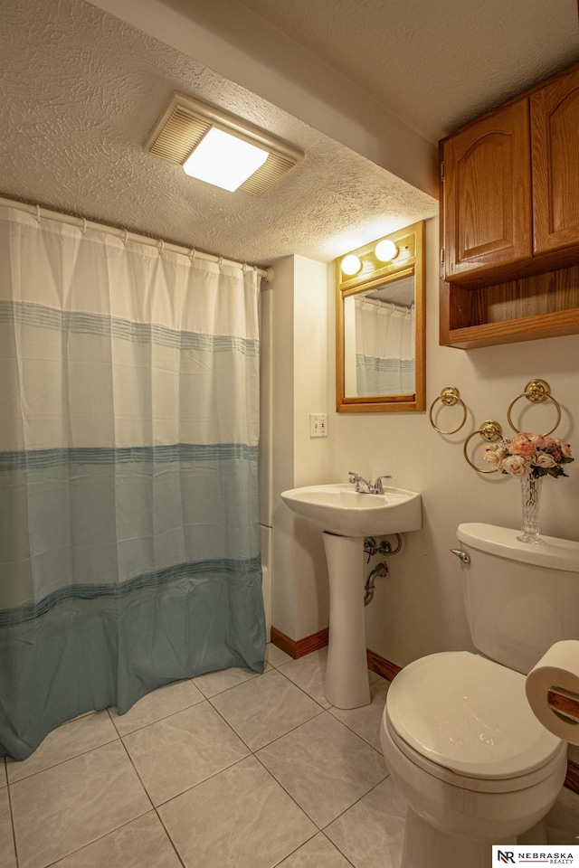 bathroom with sink, tile patterned flooring, a textured ceiling, curtained shower, and toilet