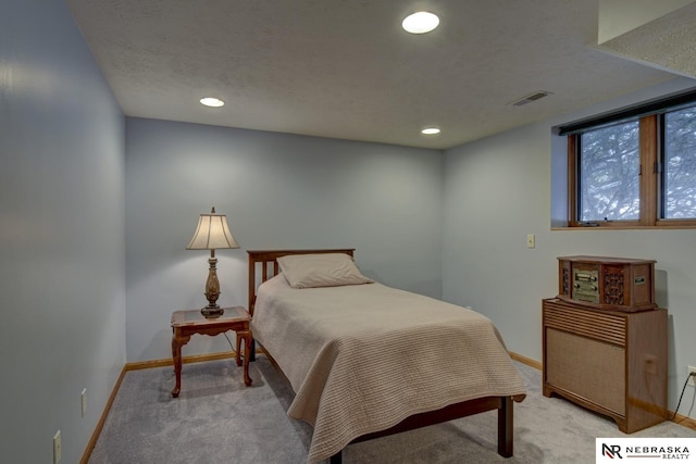 bedroom featuring light colored carpet and a textured ceiling