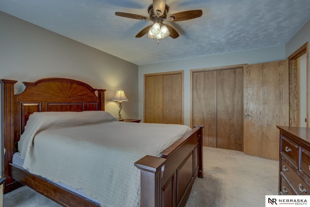 bedroom featuring multiple closets, ceiling fan, and light carpet