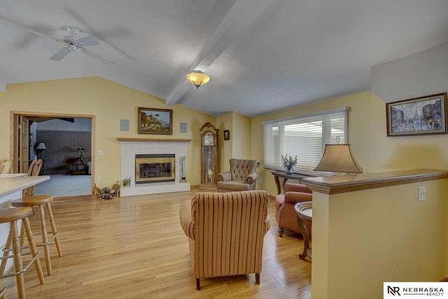 living room with ceiling fan, light hardwood / wood-style floors, and vaulted ceiling with beams