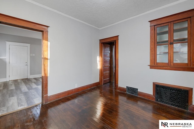 spare room featuring crown molding, a textured ceiling, and dark hardwood / wood-style flooring