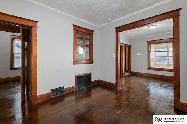 empty room featuring dark hardwood / wood-style flooring, ornamental molding, and a textured ceiling