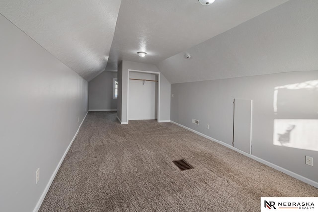 bonus room with lofted ceiling, carpet flooring, and a textured ceiling