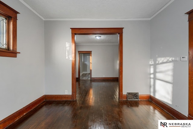 empty room with dark wood-type flooring, ornamental molding, and a textured ceiling