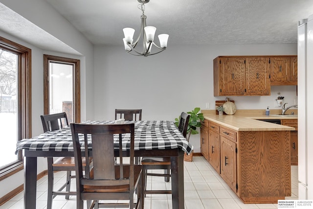 tiled dining area featuring a notable chandelier, sink, a textured ceiling, and a wealth of natural light