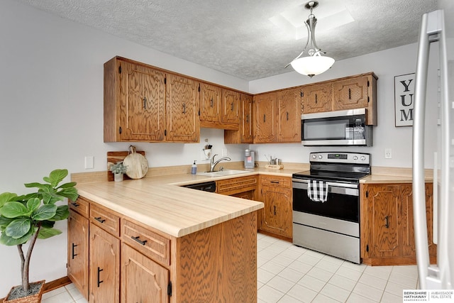 kitchen featuring pendant lighting, sink, stainless steel appliances, a textured ceiling, and kitchen peninsula