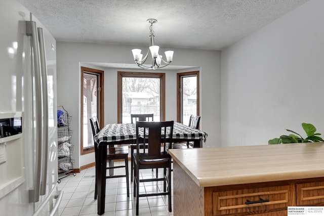 dining space with light tile patterned floors, a textured ceiling, and a chandelier