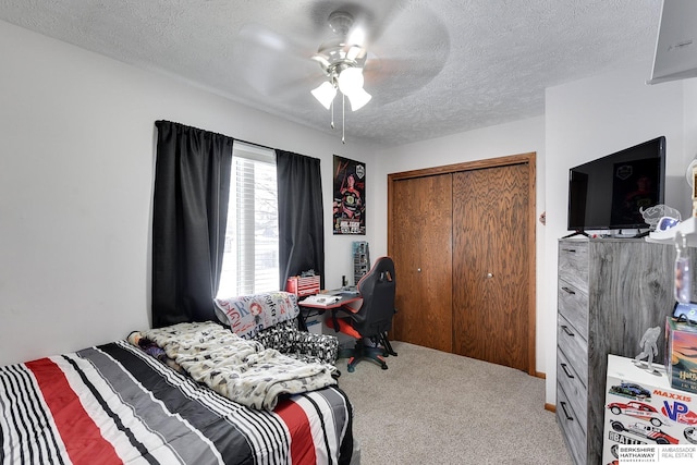 bedroom with ceiling fan, a closet, carpet, and a textured ceiling