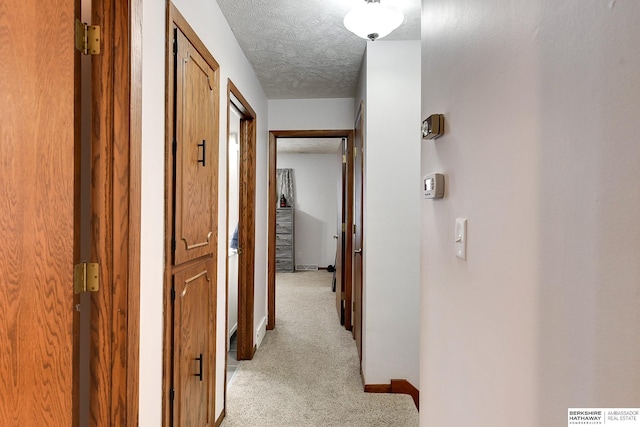 corridor featuring light carpet and a textured ceiling