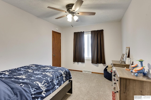 carpeted bedroom featuring ceiling fan and a textured ceiling