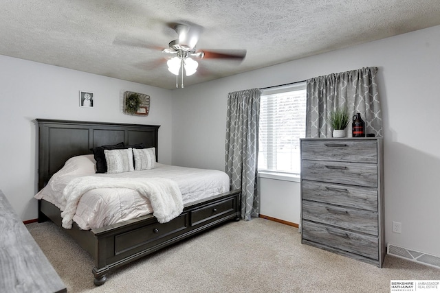 bedroom featuring ceiling fan, light carpet, and a textured ceiling