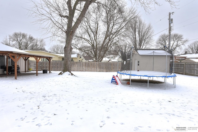 snowy yard featuring a gazebo and a trampoline