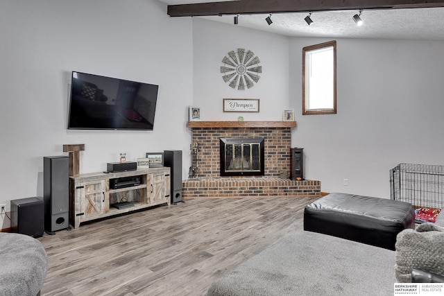 living room with wood-type flooring, a brick fireplace, lofted ceiling, and a textured ceiling