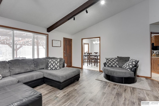 living room featuring track lighting, wood-type flooring, a chandelier, and lofted ceiling with beams