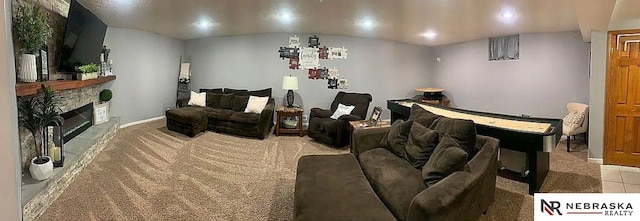 carpeted living room with a stone fireplace