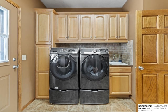 laundry area with cabinets, washing machine and dryer, and sink