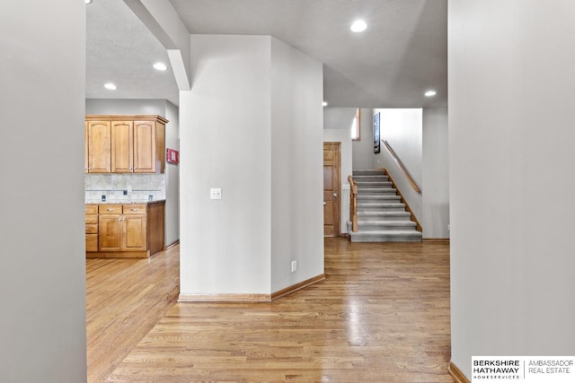 interior space with backsplash, light hardwood / wood-style floors, and a textured ceiling