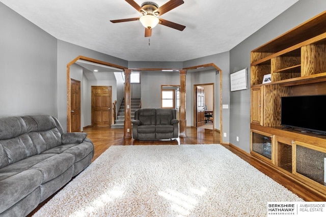 living room featuring ceiling fan, dark hardwood / wood-style floors, and decorative columns