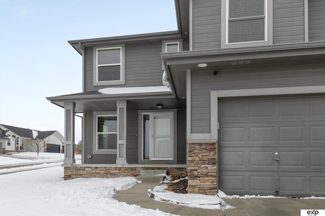 snow covered property entrance with a garage