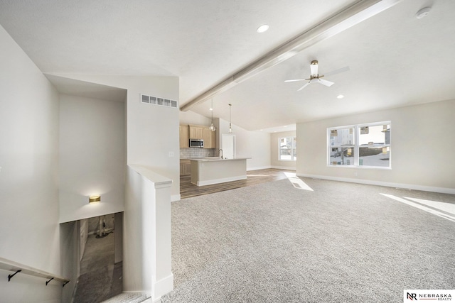 unfurnished living room with vaulted ceiling with beams, light colored carpet, sink, and ceiling fan