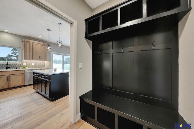 mudroom with plenty of natural light, sink, and light hardwood / wood-style flooring