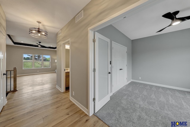 corridor featuring a raised ceiling and light hardwood / wood-style flooring