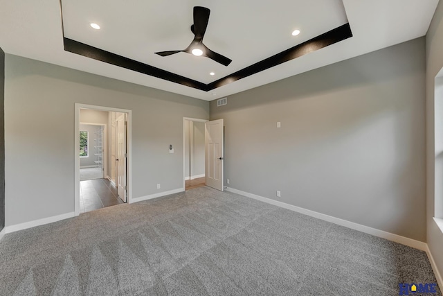 unfurnished bedroom with a raised ceiling, carpet flooring, and ceiling fan