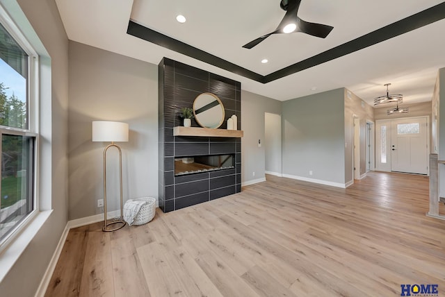 unfurnished living room featuring a tile fireplace, plenty of natural light, and light wood-type flooring