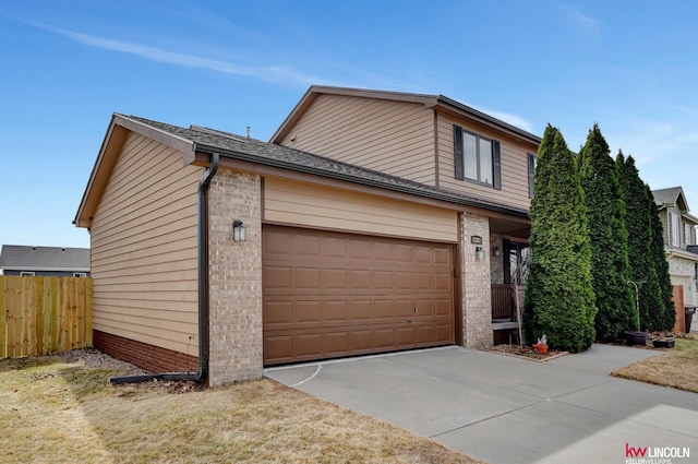 traditional-style house featuring a garage, fence, brick siding, and driveway