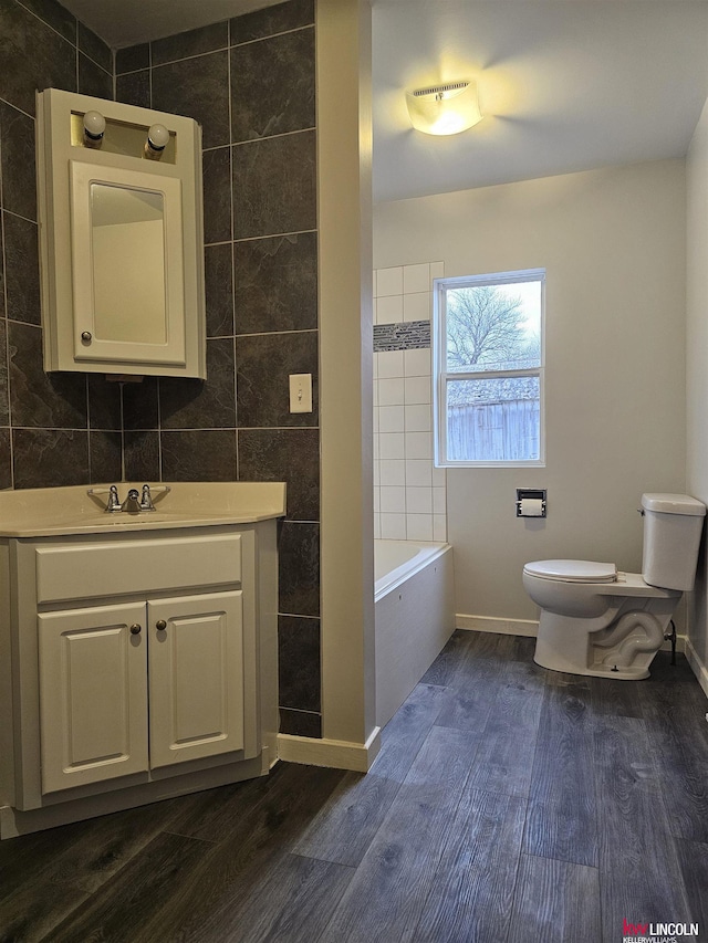 bathroom featuring hardwood / wood-style flooring, vanity, toilet, and tile walls